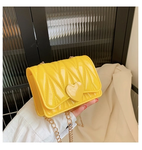 Detail of a bright yellow silicone heart bag featuring radial texture and a gold chain strap