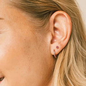 Close-up of rose gold S925 sterling silver earrings set with red crystals on model