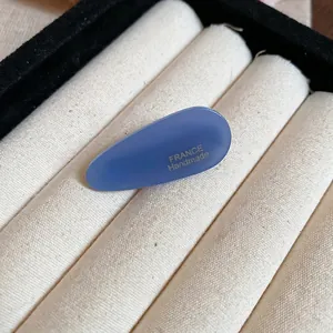 Pince à cheveux ovale en acrylique bleu clair avec texte France Handmade sur tissu