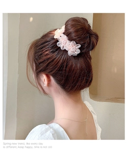 Detailed close-up of light pink mesh flower hair clip with white beads on model