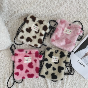 Detail view of heart pattern plush mini bags in multiple colors with woven straps