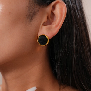 Close-up of vintage round earrings with gold metal frame and black flocking on model's ear