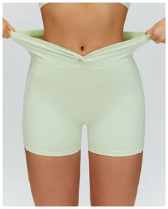 Dettaglio del design a vita incrociata elastica dei pantaloncini da yoga verde menta tesi