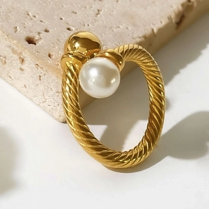 Vintage gold twisted rope ring with pearl inlay on beige stone background