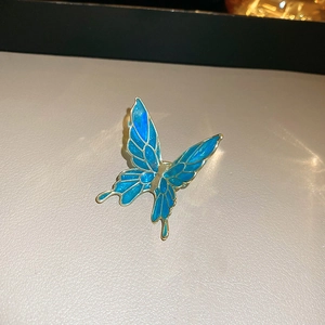 Close-up of a blue butterfly clip with vintage enamel finish and golden metal edges
