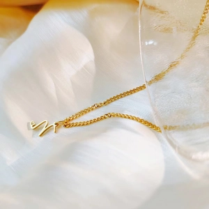 Elegant gold titanium steel necklace featuring a heart initial M pendant detail view