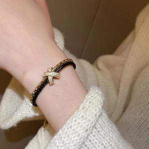 Gros plan d'un bracelet double couche avec un charm en croix plaqué or serti de zircon