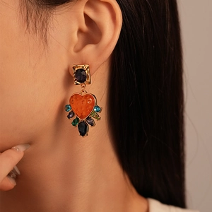 Close-up of vintage heart earrings with colorful resin gems on a female model