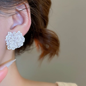Macro shot of white flower earring with fine crackle texture and French retro design