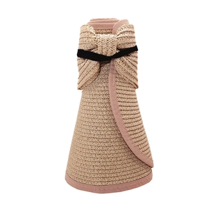 Folded straw sun visor with pink trim and bow showing portable rollup design