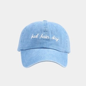 Close-up of bad hair day white embroidery on washed blue denim cotton baseball cap