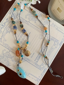 Detail of bohemian turquoise beaded necklace with eye pendant on vintage card