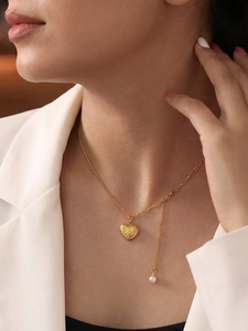 Détail du collier coeur doré avec surface texturée et goutte de perle délicate