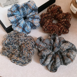 Détail de quatre chouchous en tricot et à carreaux bleu, marron, gris sur fond épuré