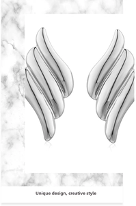 Macro detail of silver wing earrings featuring polished irregular metal texture
