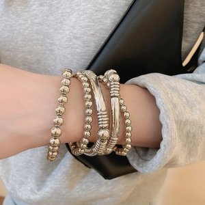 Gros plan détaillé de bracelets en métal argenté avec perles polies et tubes texturés