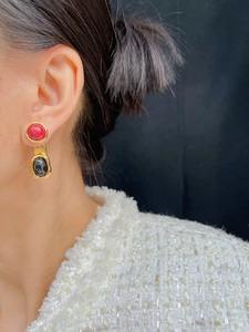Gros plan de boucles d'oreilles vintage dorées avec émail rouge et noir sur un mannequin