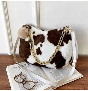Detail of plush cow print tote bag with thick gold chain and faux fur texture details