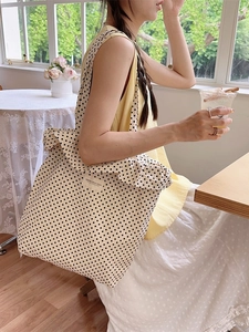 Polka dot canvas tote bag with ruffle trim shown in a cozy indoor lifestyle setting