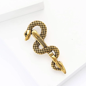 Golden snake and staff brooch with textured metal scales on a minimalist white stand