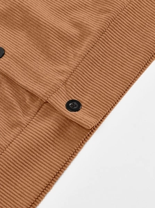Close-up of a brown ribbed knit cardigan featuring a black button and heavy texture
