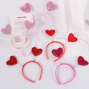 Flat lay of multiple Valentine red and pink sequin heart headbands on white background