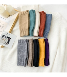 Flat lay of colorful ribbed knit fingerless gloves and wrist warmers on a white sweater