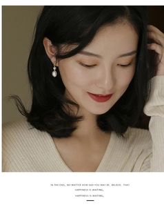 Detail of freshwater pearl drop earrings with gold hooks on model's ear