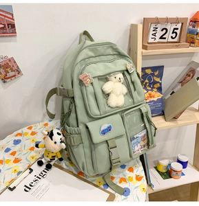 Dettaglio dello zaino in nylon verde chiaro con multitasche e ciondolo a forma di orso