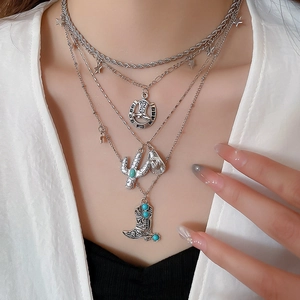 Macro detail of silver layered necklace with western charms and green turquoise pendants