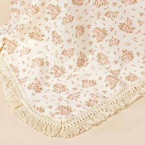 Detailed macro of floral baby blanket fabric with delicate beige woven tassels
