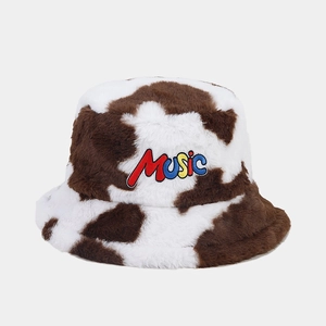Macro detail of plush cow print bucket hat with embroidered colorful MUSIC letters