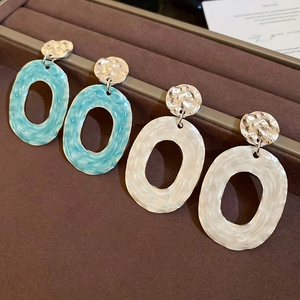 Detail of oval hollow drop earrings in light blue and cream marble with hammered silver studs
