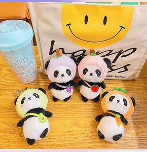 Set of four plush panda keychains with colorful fruit and vegetable hats on wooden surface