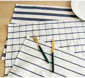 Detail of blue striped and checkered cotton linen napkins layered on wooden table
