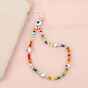 Bijou de téléphone bohème en argile colorée avec œil porte-bonheur sur fond rose