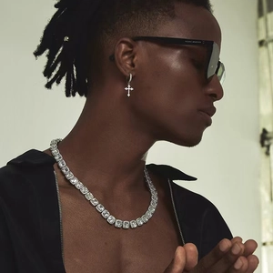 Close-up of hip-hop silver cross earrings and sparkling square zircon tennis necklace on model