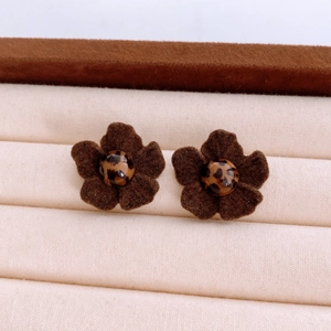 Macro detail of brown flocked flower earrings with leopard print center on display