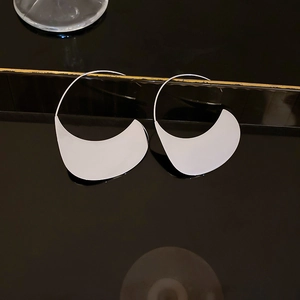 Macro shot of silver crescent geometric earrings in polished stainless steel