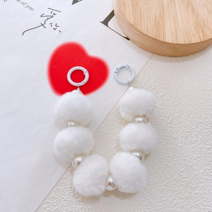 Detailed view of white faux pearl and plush fur pompom keychain with metal spring ring