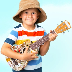 Smiling child holding a small ukulele decorated with colorful cat face collage stickers