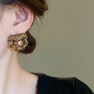 Détail de boucles d'oreilles vintage en forme de coquillage doré avec perles et strass marron