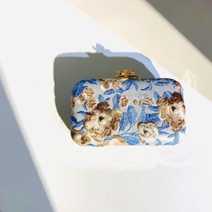 Detailed embroidery with floral patterns and pearl accents on elegant evening clutch