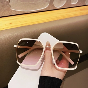 Detail view of large white square frame sunglasses with gold temples and gradient lenses