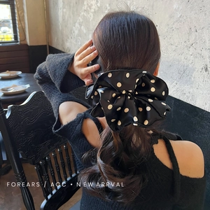Close-up of elegant black and white polka dot satin scrunchie on a model's ponytail