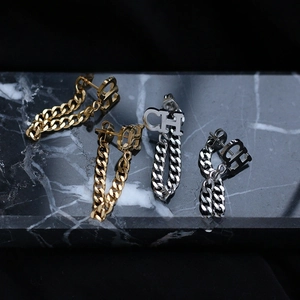 Macro shot of gold and silver plated titanium steel earrings with CH logo and chains