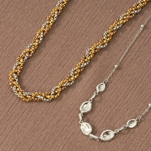 Dettaglio ravvicinato di catene in oro e argento su sfondo di tessuto twill marrone