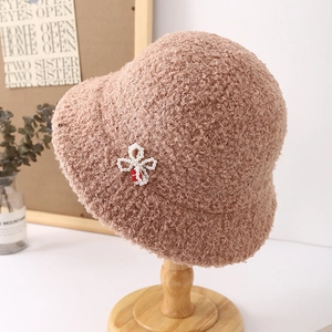 Detalle de gorro de lana de cordero marrón claro con lazo de perlas en soporte de madera