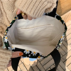 Detail view of the black canvas daisy tote bag showing internal pocket and lining