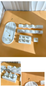 Detailed view of white geometric jewelry trays and golden earrings on orange background